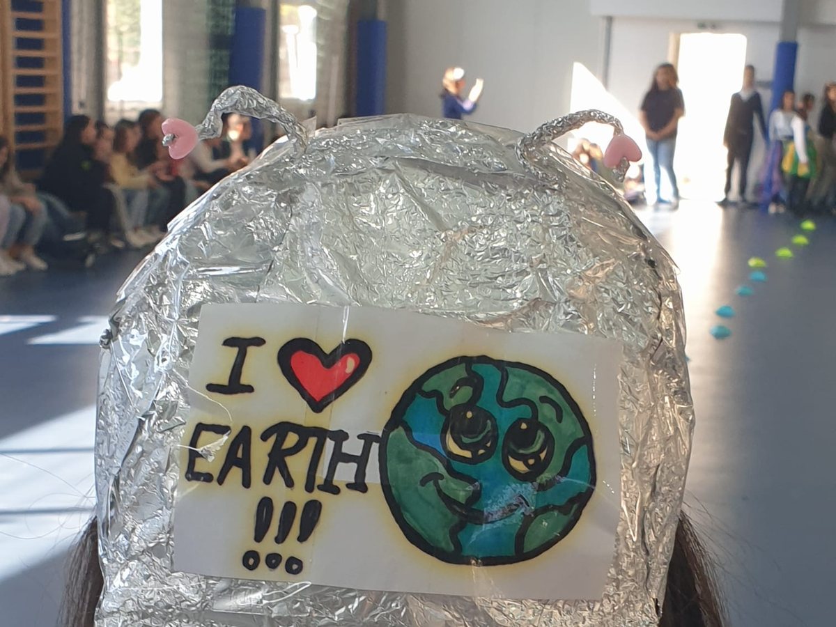 Copil într-o sală de sport, cu o șapcă din folie pe care scrie „I love Earth”, la un atelier de educație ecologică