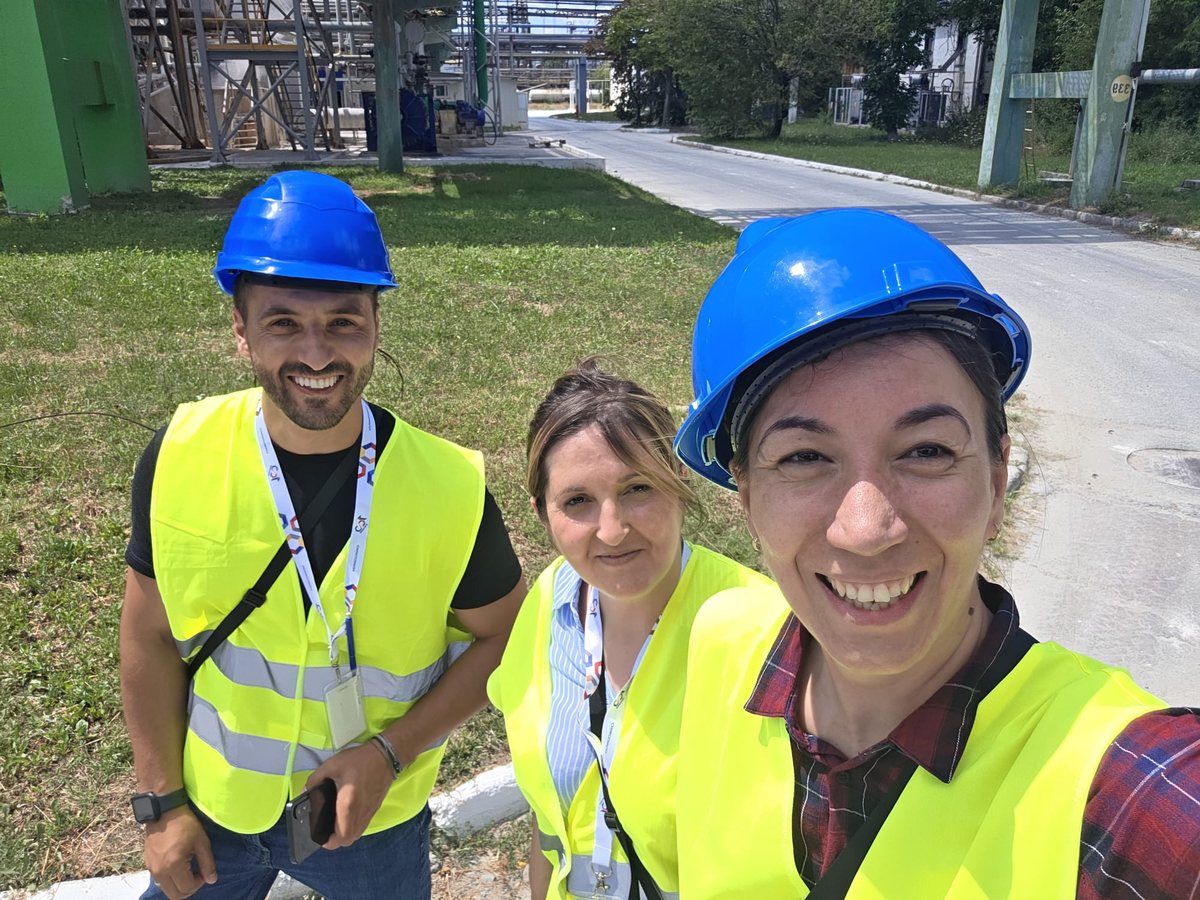 Trei consultanți GIS, cu căști și veste de protecție, în vizită pe o platformă industrială